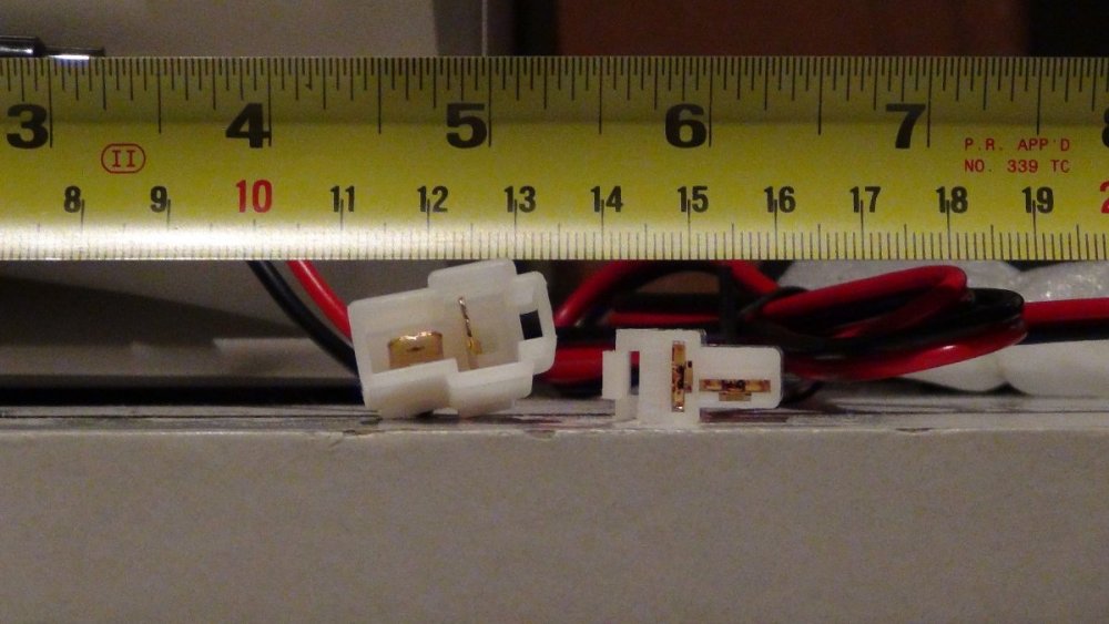 A male and female 2-pin T-connector with a ruler viewed head-on.